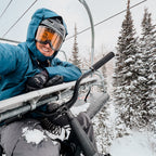 Person on a ski lift with snowy trees in the background